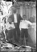 Retrato de um homem e duas crianças, numa varanda, em local não identificado