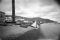 Vista oeste/este da praia da cidade do Funchal com barcos varados e o Pilar de Banger