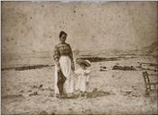 Mulher e uma menina, numa praia, em local não identificado 