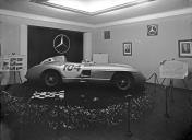 Automóvel de competição Mercedes-Benz, modelo W196 com o n.º 104 na porta, no interior do stand representante da marca Mercedes-Benz