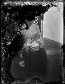 Retrato de uma mulher e um bebé, no pátio de uma casa, em local não identificado