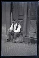 Homem sentado na soleira de uma porta, em local não identificado, na Ilha da Madeira