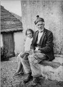 Retrato de um idoso e uma menina sentados num banco, no exterior de uma casa, Freguesia da Camacha, Concelho de Santa Cruz