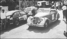 Automóvel Jaguar MK V Roadster (1965) do piloto José Silva Faria, participante no 2.º Raid Diário de Notícias, cruza-se com um moderno automóvel de competição da prova Rampa Aniversário do Marítimo, em local não identificado