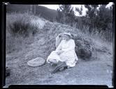 Jean Ruby Blanche Shaw, numa paisagem florestal, sentada no chão e encostada a uma rocha