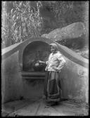 Retrato de mulher junto a um fontanário em local não identificado (corpo inteiro)
