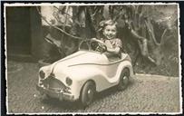 Retrato do menino Boaventura António num automóvel de brincar em local não identificado