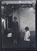 Retrato de mulher e de uma criança no quintal de uma casa