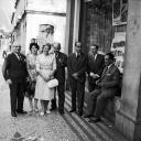 José Maria Ferreira de Castro e esposa, Elena Muriel, acompanhados por quatro homens e uma senhora, junto à montra da casa fotográfica "Perestrellos Photographos", na avenida Arriaga, Freguesia da Sé, Concelho do Funchal
