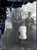 Retrato de uma jovem e três crianças, no pátio de uma casa, em local não identificado 