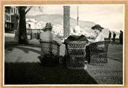 Um homem e duas mulheres, sentados em cadeiras de vime, na esplanada do restaurante "Phenix", na praça Marquês de Pombal (atual avenida do Mar e das Comunidades Madeirenses), Freguesia da Sé, Concelho do Funchal